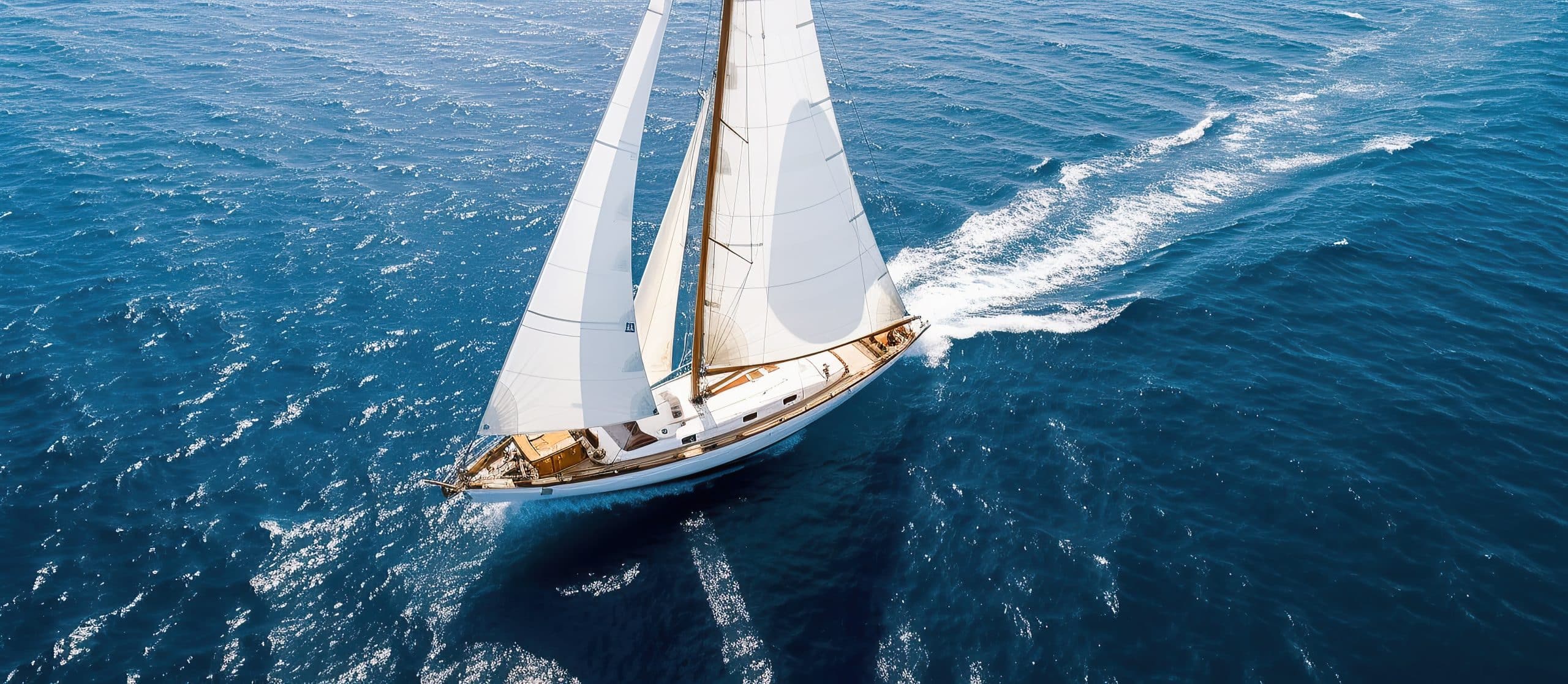 Home 1 Regatta yacht with white sails sailing on the open blue sea during bright blue sky